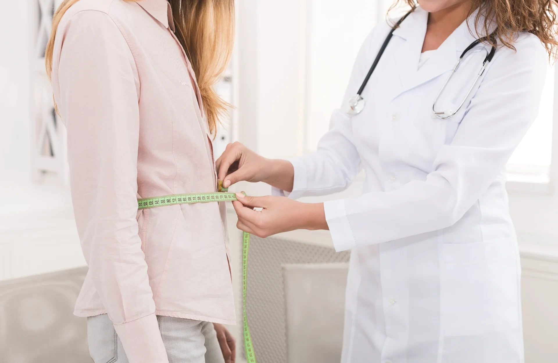 Ärztin misst den Taillenumfang einer Patientin